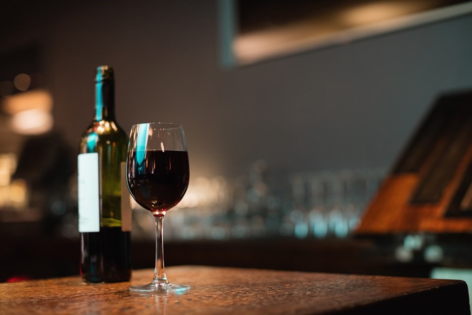 copo-de-vinho-tinto-e-garrafa-no-balcao-de-bar
